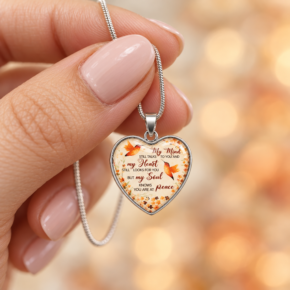 Heart-shaped hummingbird memorial necklace with orange floral details and the message “My soul knows you are at peace.”