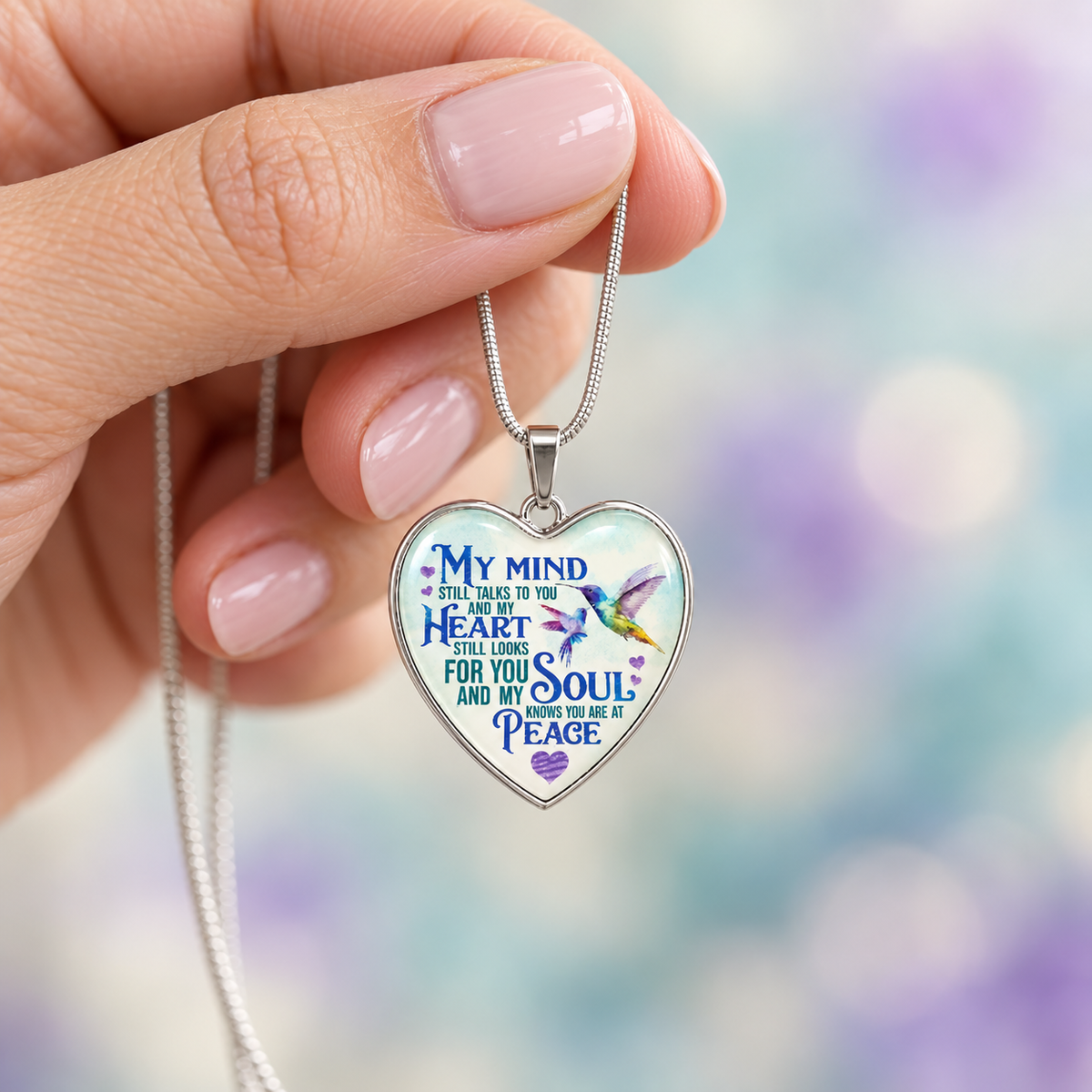 Heart-shaped memorial necklace with two blue and purple hummingbirds and the message “My soul knows you are at peace.”
