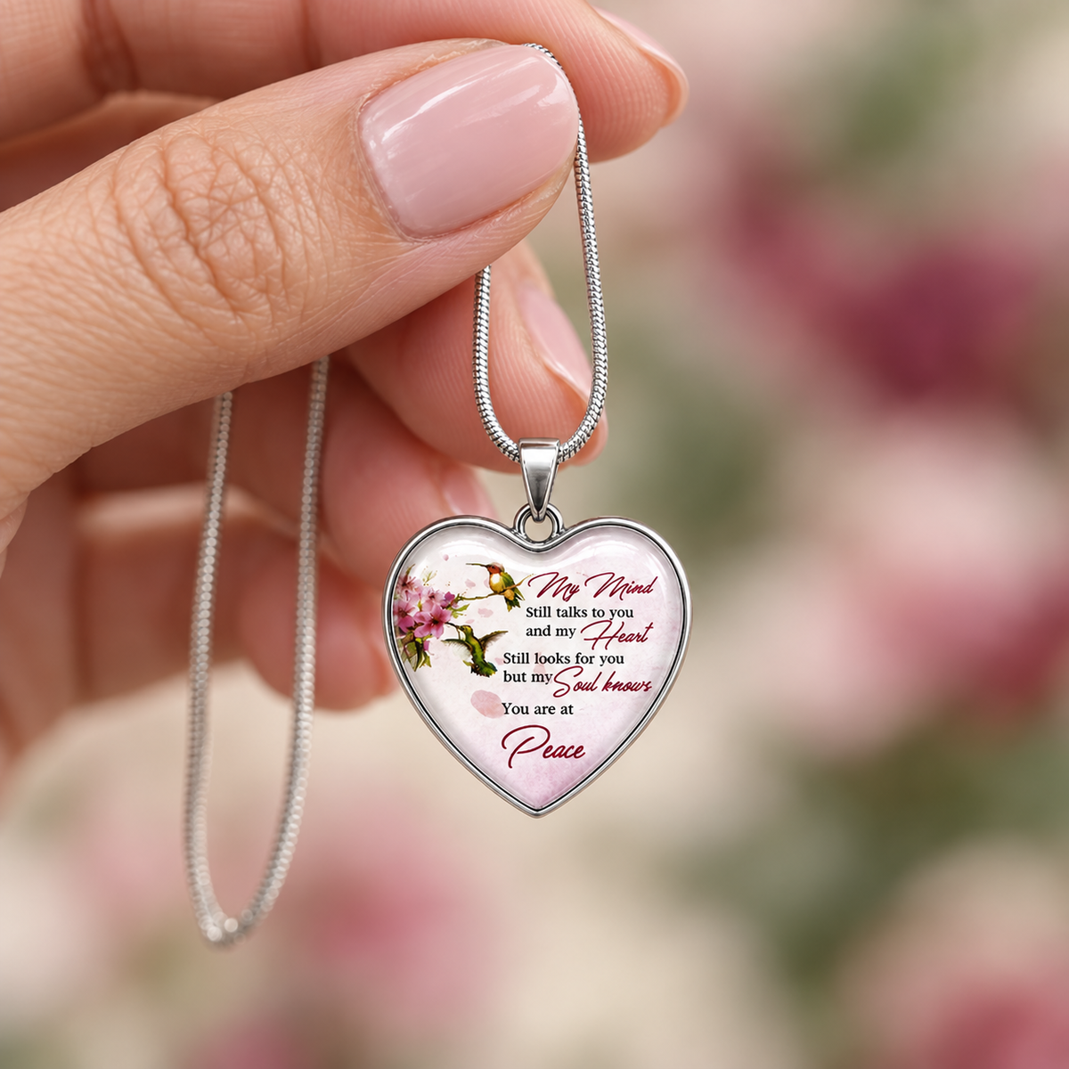 Heart-shaped pendant with floral design and remembrance text on a soft background