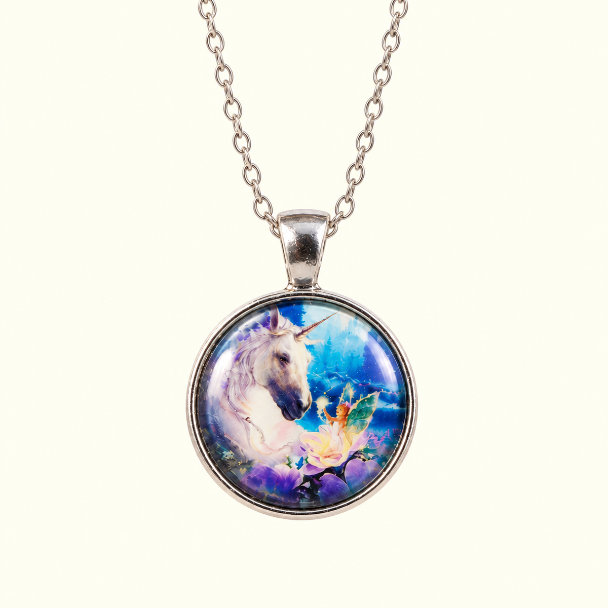 A silver chain necklace with a round pendant featuring a colorful fantasy illustration of a white unicorn and a fairy on a blue and purple background, shown against a light cream backdrop.