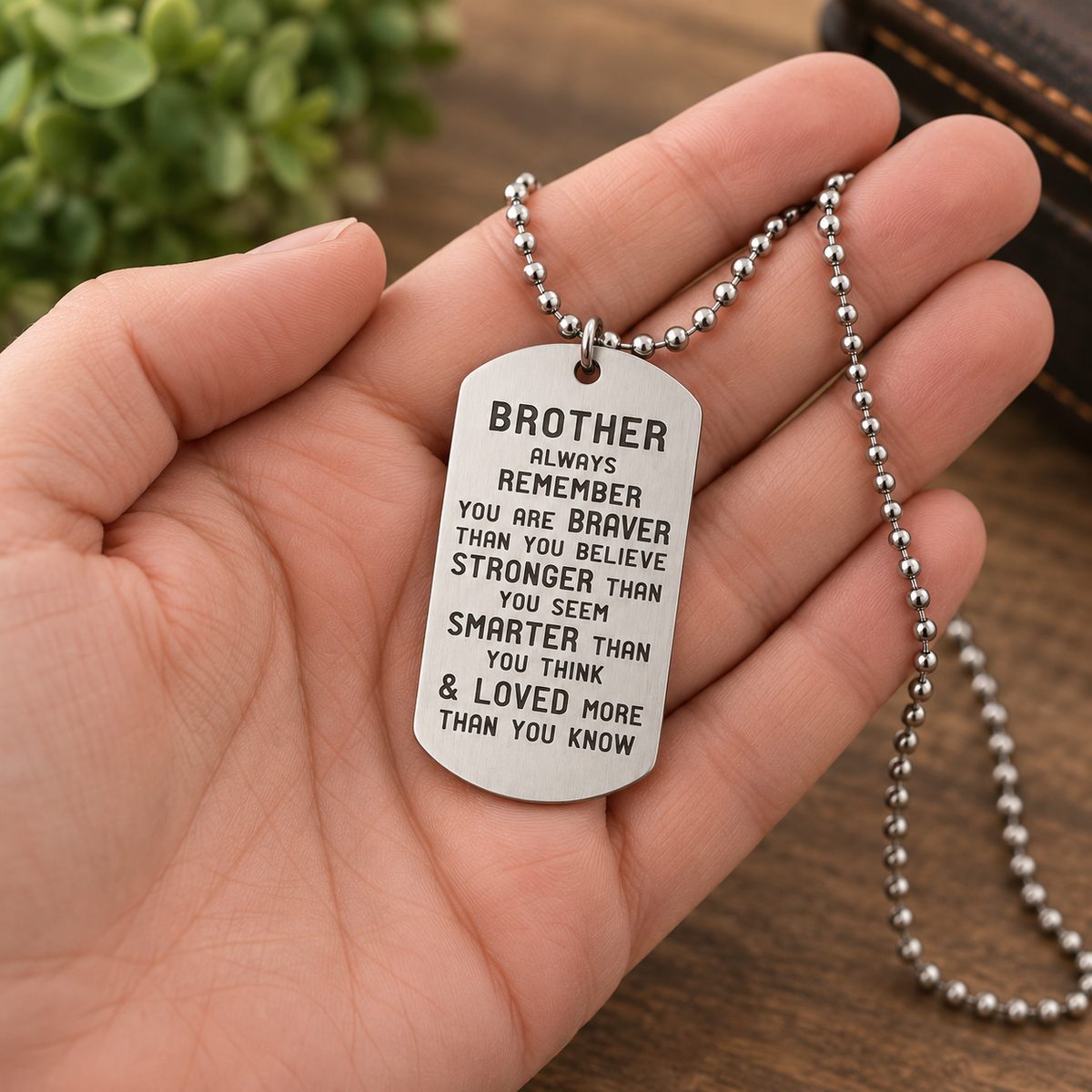 image of a hand holding a dog tag style necklace that reads brother always remember you are braver than you believe stronger than you seem smarter than you think and loved more than you know