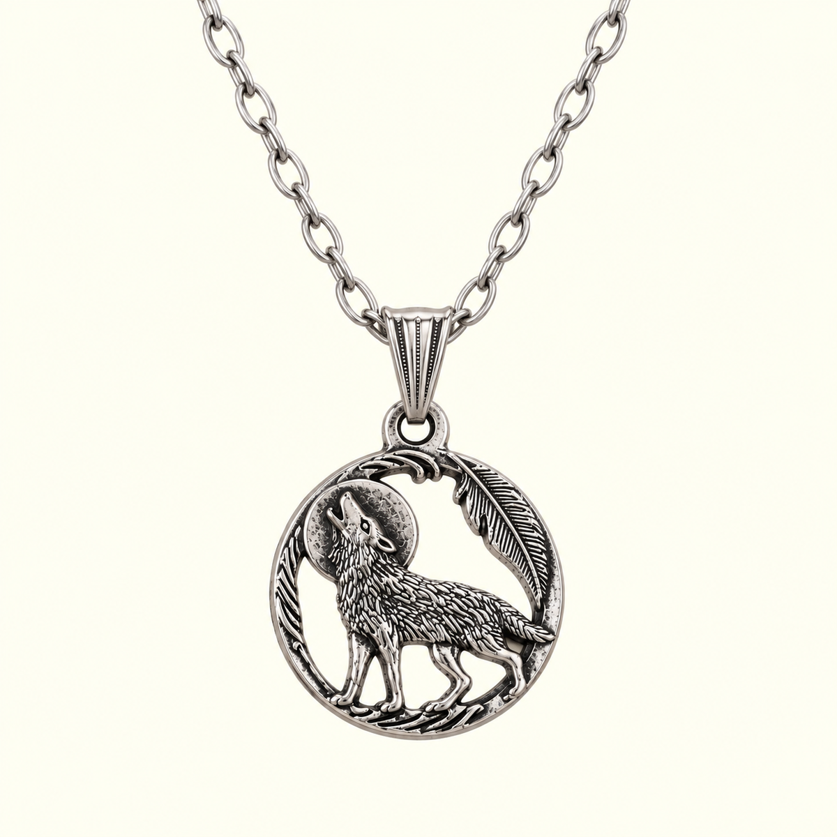 A silver-toned pendant necklace featuring a detailed circular charm with a howling wolf, a feather, and a crescent moon, suspended from a matching link chain against a light cream background.
