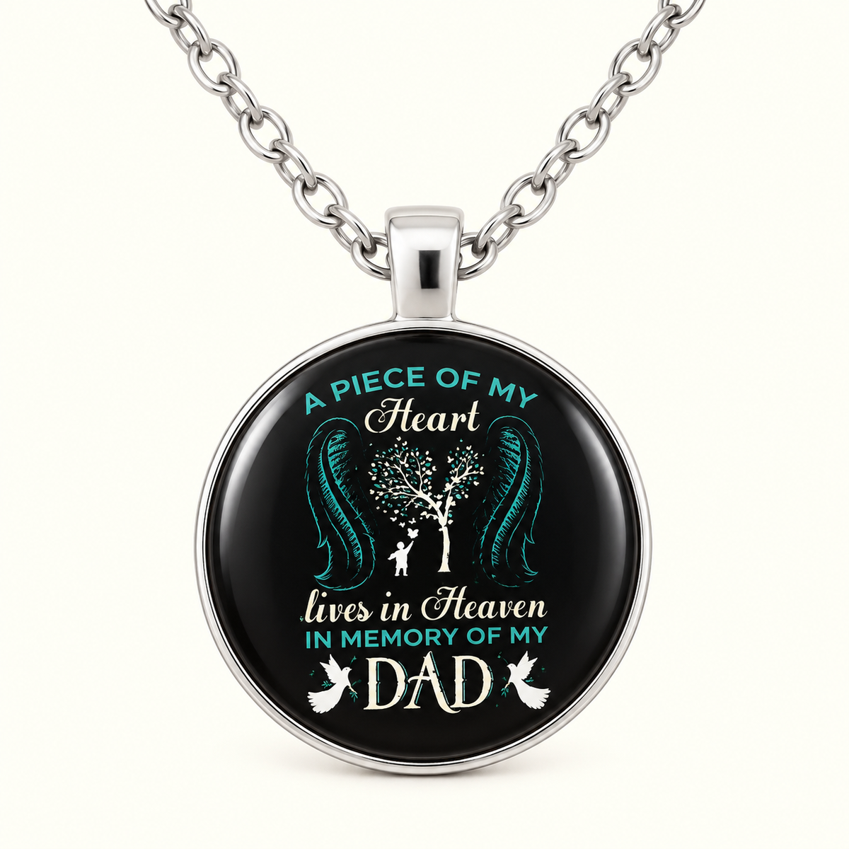 A silver pendant necklace with a circular black face featuring a memorial design for 'Dad' in teal and white text and artwork, shown on a plain light background.