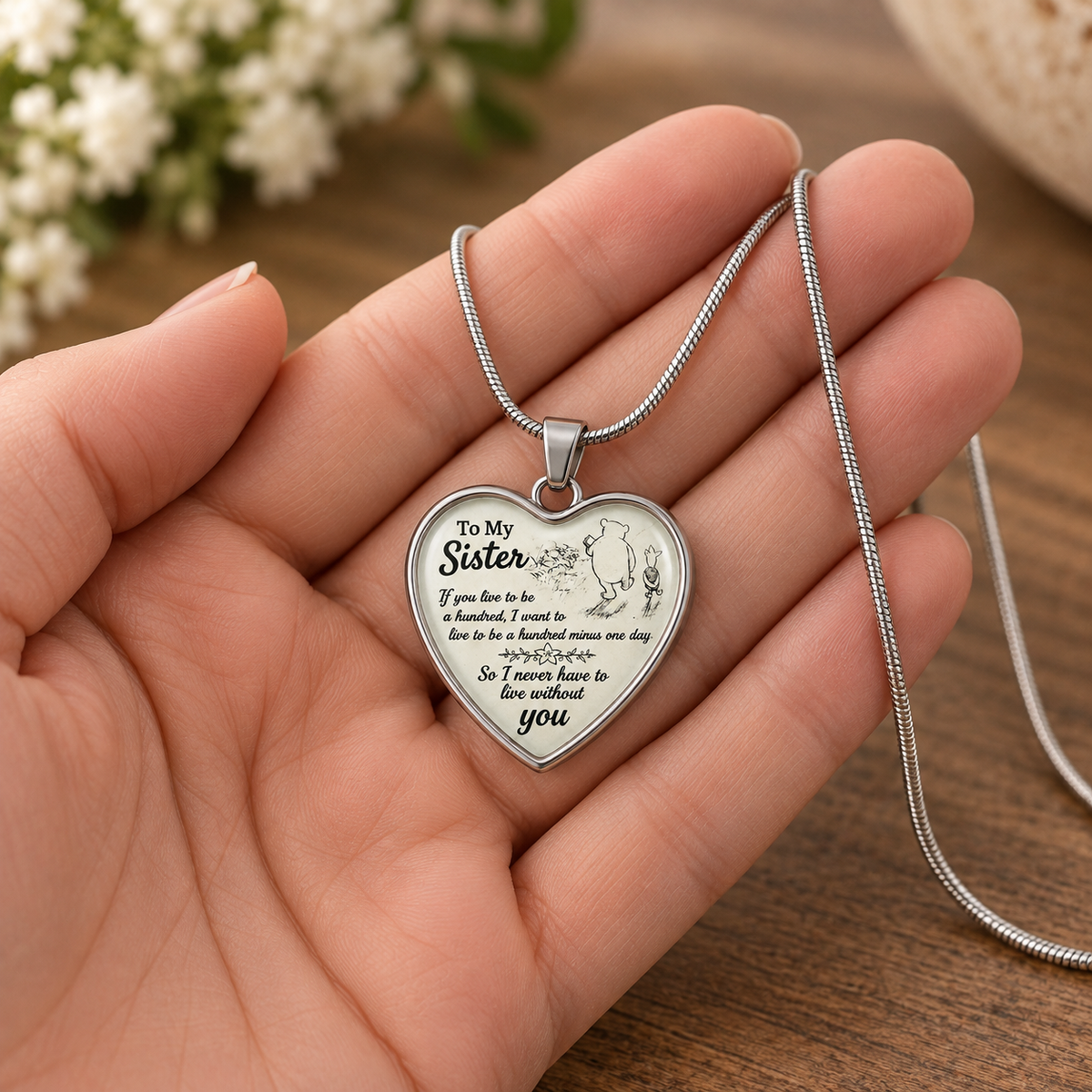 image of a hand holding a heart shaped pendant with pooh and piglet which reads to my sister if you live to be a hundred, i want to live to be a hundred minus one day so I never have to live without you
