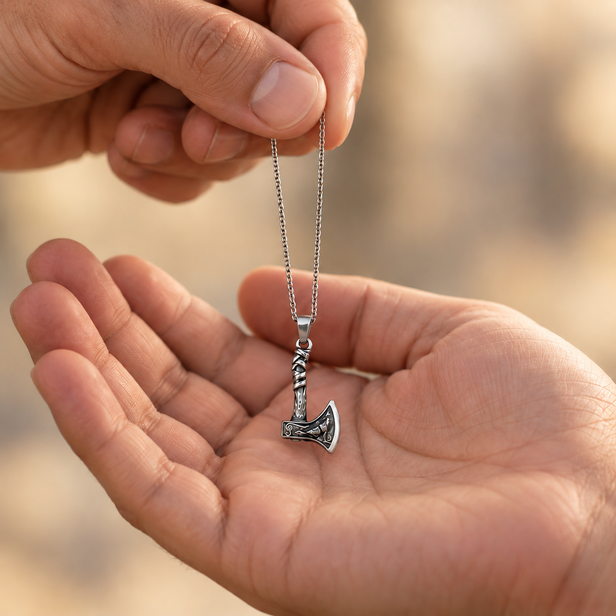 image of a necklace being given to some, the necklace features a silver chain and silver hatchet with a howling wolf